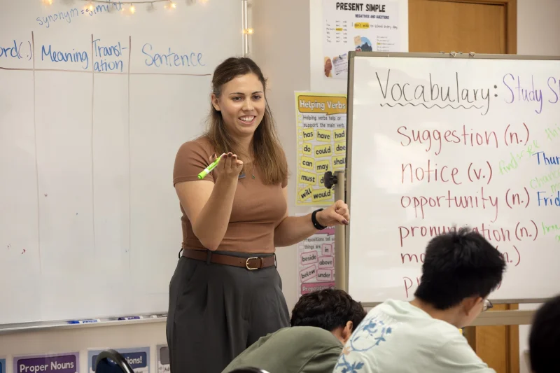 Female Tianjin International School teacher instructing new vocabulary on the white board