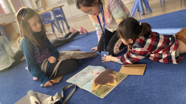 two young female students and teacher at tianjin international school about reading a children's book