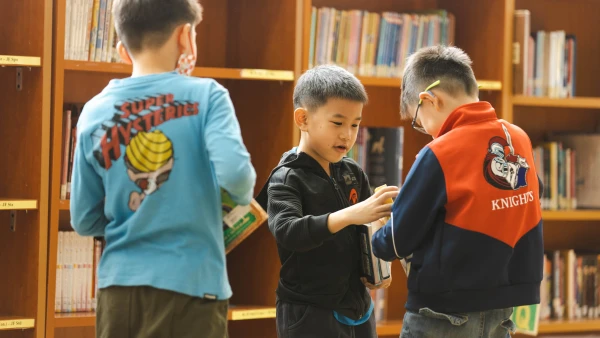 three male students finding books in the library at the best international school in tianjin