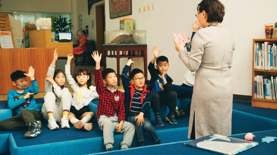 diverse young students listening to their teacher from tianjin international school about pigs and reading